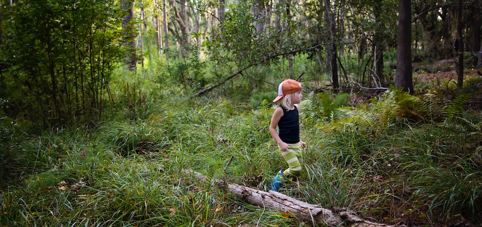 Ein Kind mit einer Kappe bei einem Waldspaziergang.